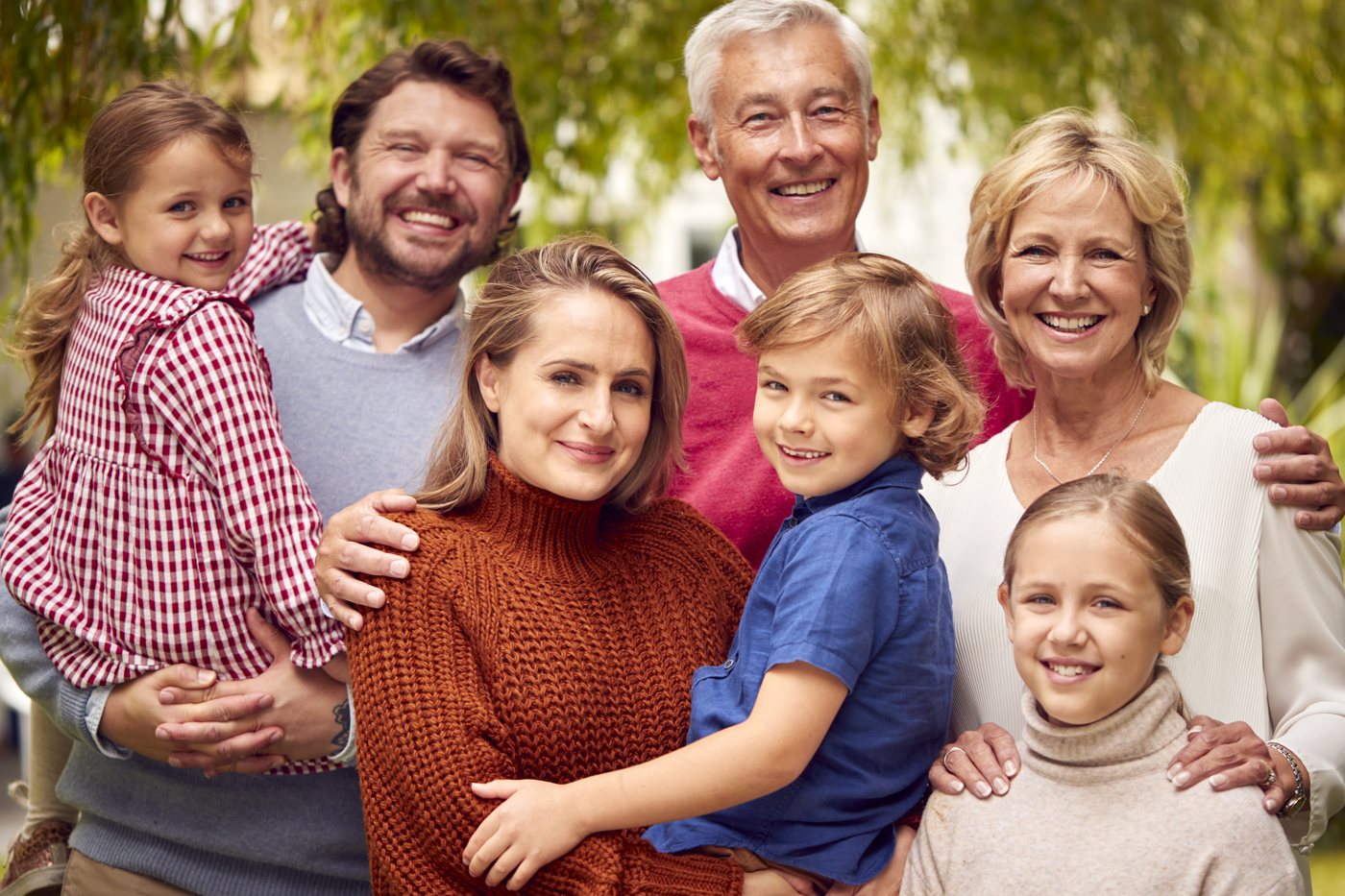 Three generations of a family smiling together outdoors